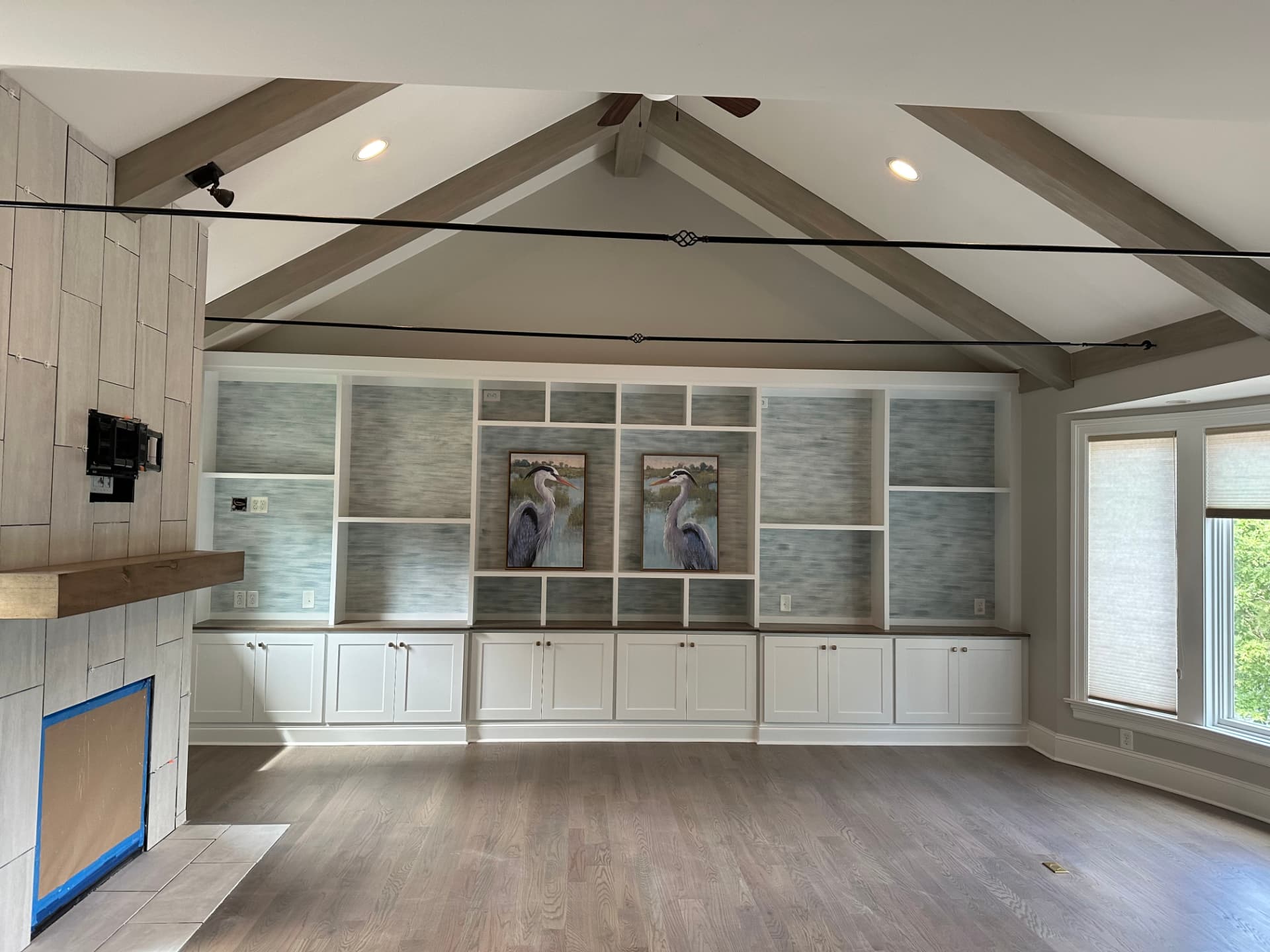 Full view of wall-to-wall custom white cabinetry and display shelving beneath a vaulted beamed ceiling