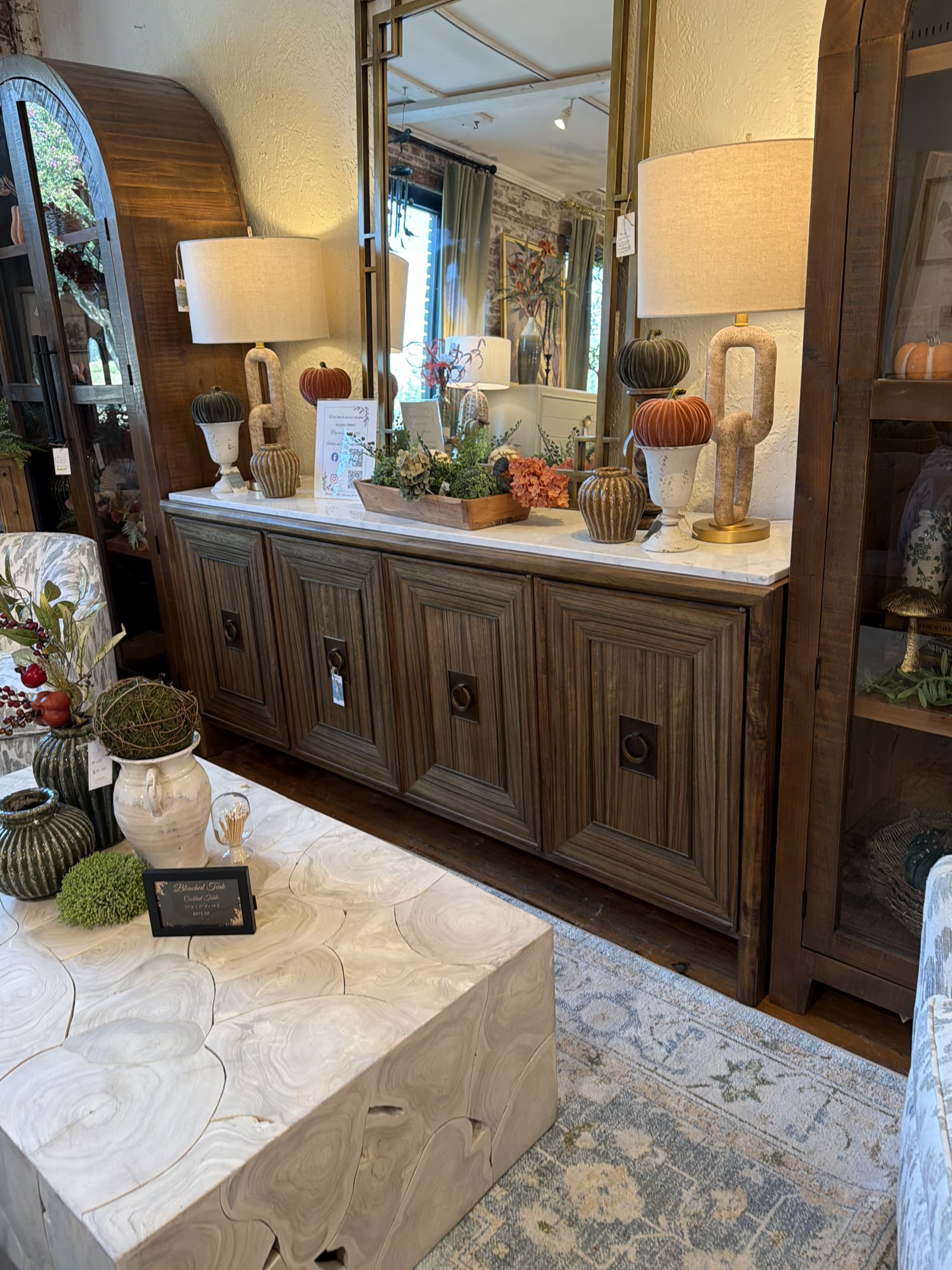 A long reeded wood sideboard with a marble top, mirror and two lamps on the sales floor at MONA