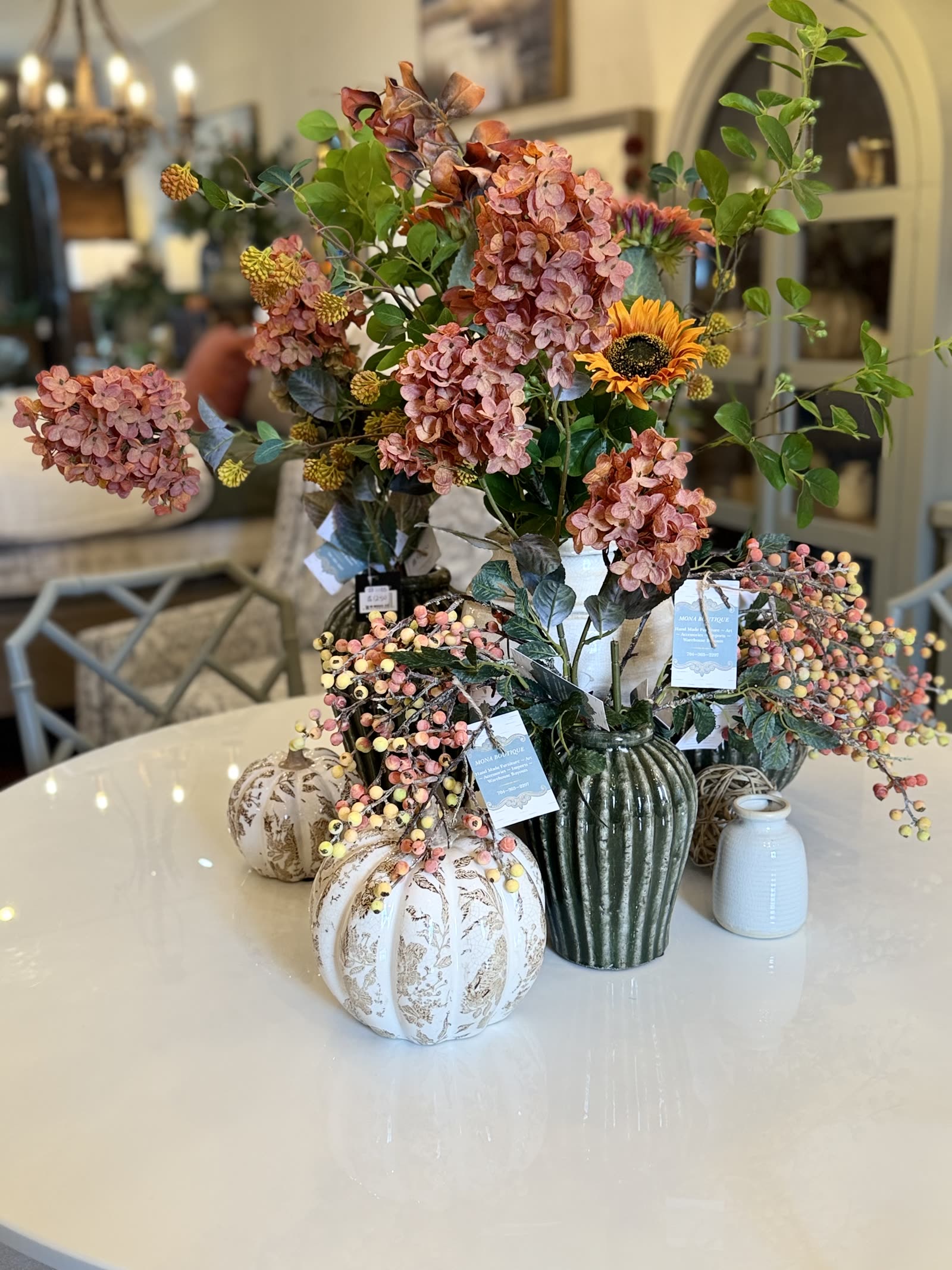 A white round dining table set with dried hydrangea arrangements, berry branches and ceramic pumpkins at MONA