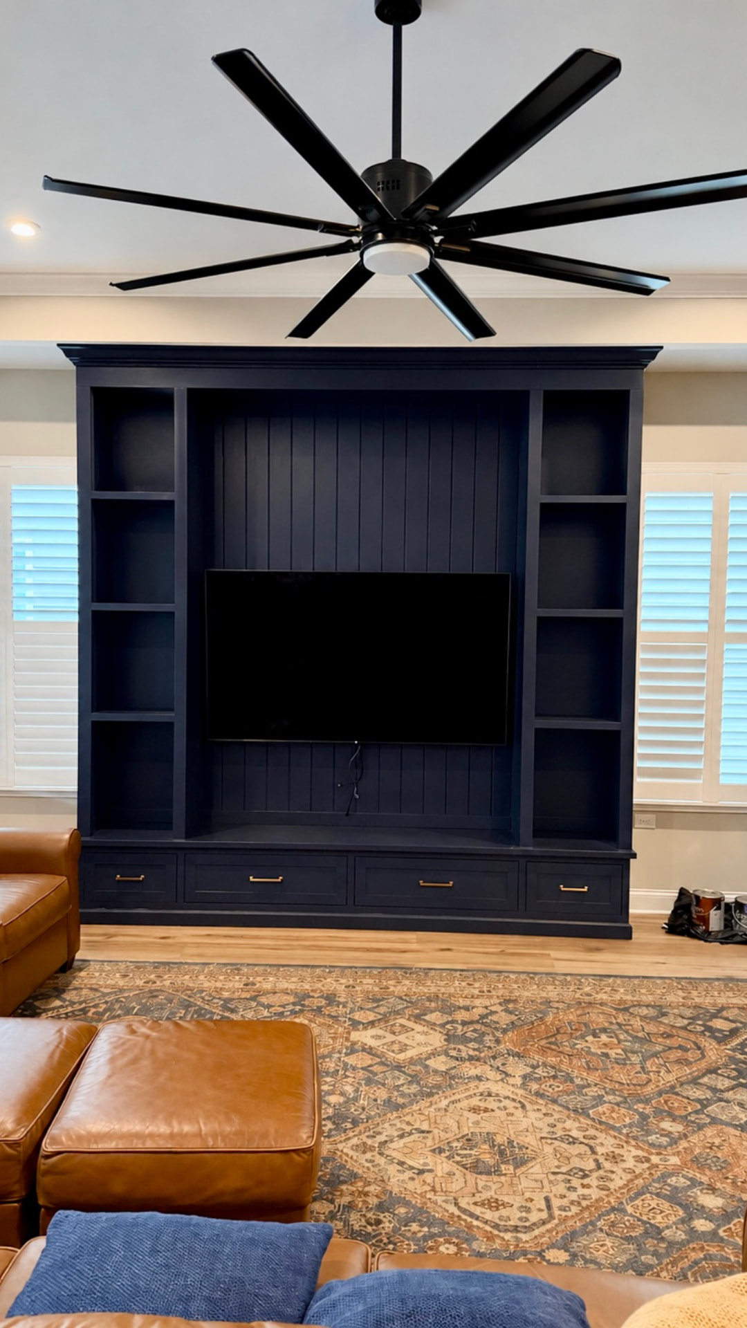 Full view of a custom deep navy entertainment center with shelving, paneled television wall and storage drawers